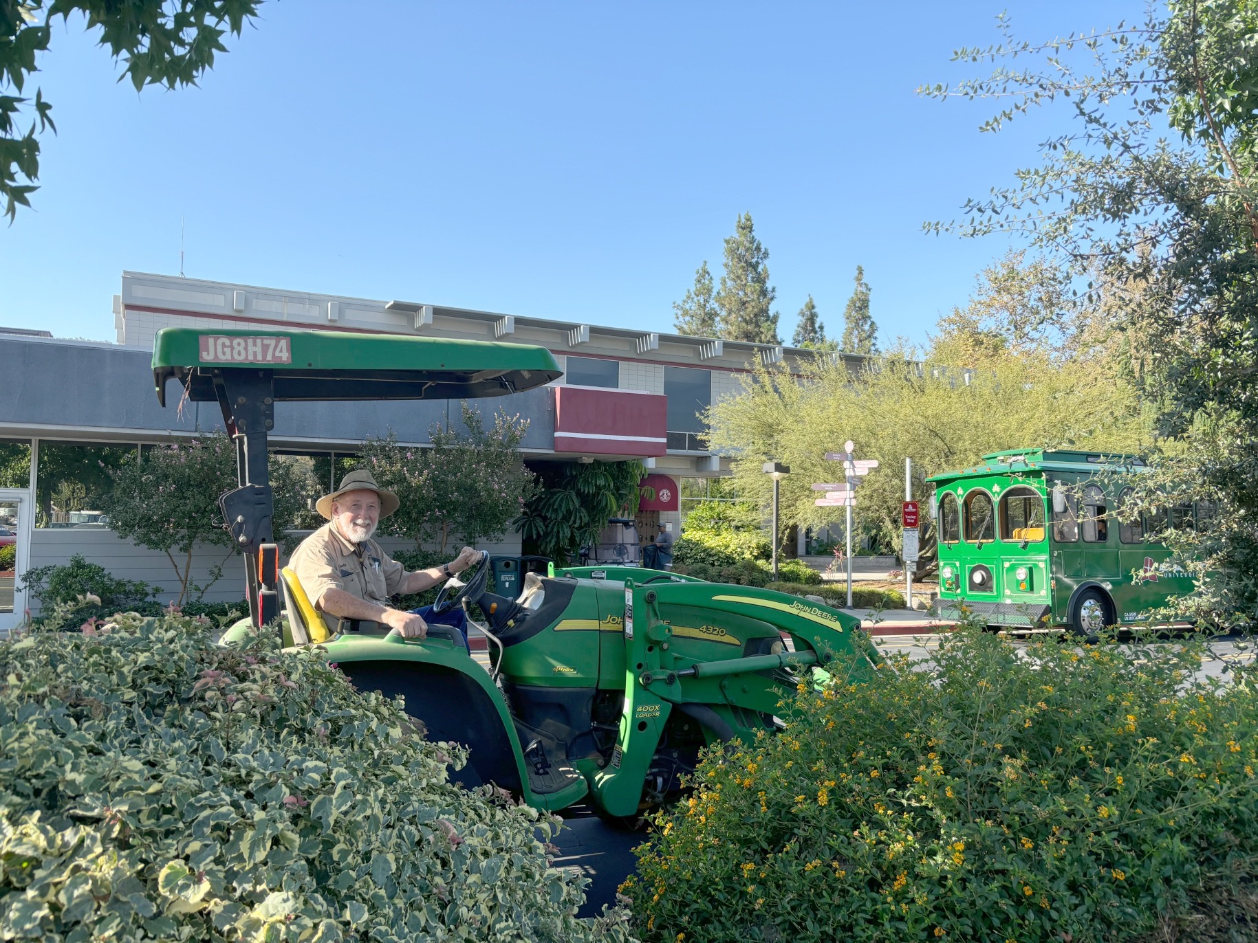 randy smiles on his tractor outside east campus